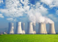 Central nuclear con campo verde y grandes nubes azules