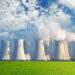 Central nuclear con campo verde y grandes nubes azules